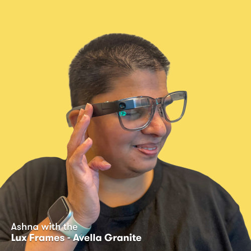 Ashna wearing the Envision Glasses with the Lux Frames - Avella Granite while having her fingers on the touchpad