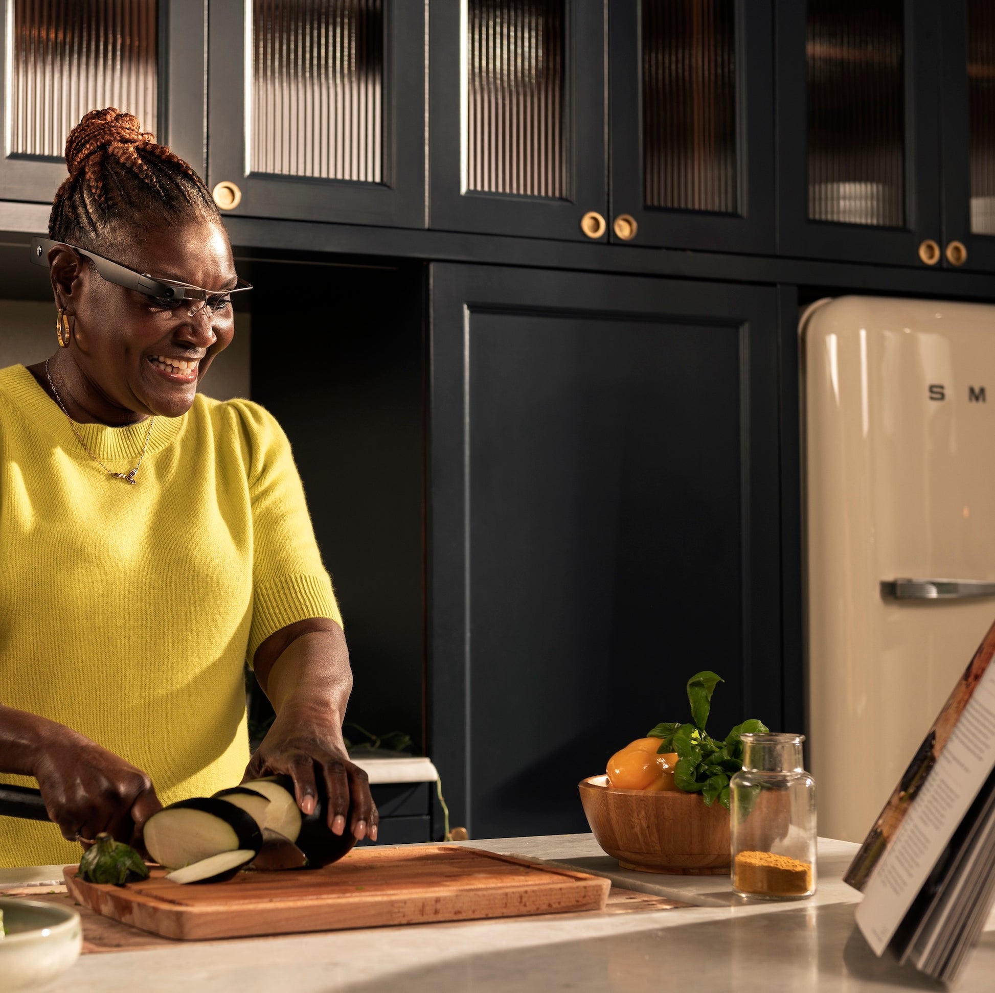 Photo of Joy, she's in the kitchen wearing Envision Glasses and reading a cookbook